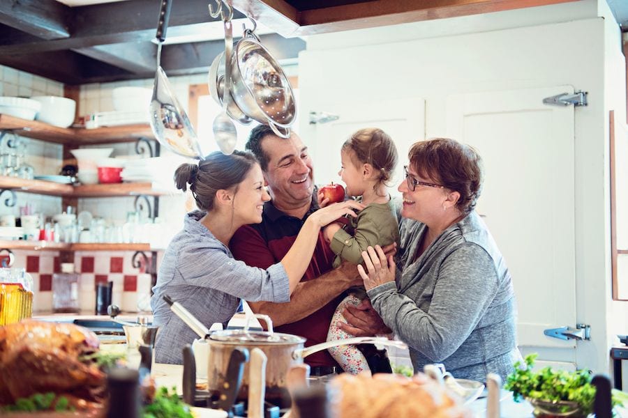 Top 10 Ways to Reduce Your Energy Bill in 2023. Image shows four family members enjoying time together in the kitchen.